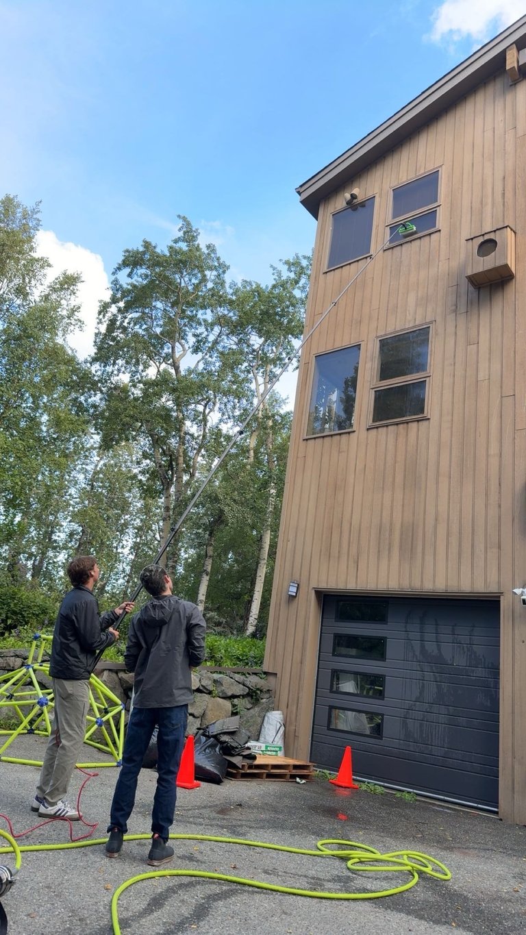 Two workers stand in front of a modern brown wooden house
