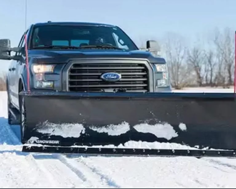 Ford pickup truck equipped with a snow plow attachment on a snowy road