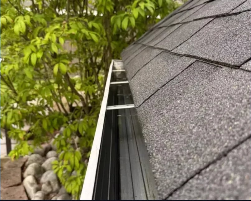 Close-up of asphalt shingle roof with metal gutter running along edge